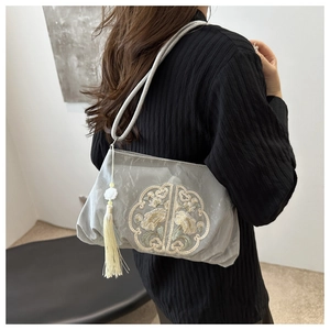 Detail of grey silk handbag featuring floral embroidery and elegant long tassel pendant