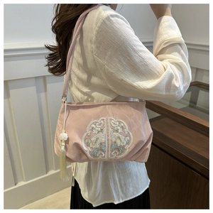 Close-up of pink satin shoulder bag with floral embroidery and elegant long silk tassel