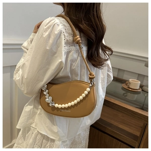Détail du sac demi-lune camel orné d'une chaîne en perles et d'un pendentif coeur argent