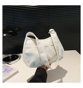 Detail of white half-moon saddle bag with wide shoulder strap and silver metal buckle
