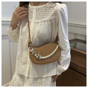 Detail of brown saddle bag with pearl heart chain and FASHION & BAGS text on the front