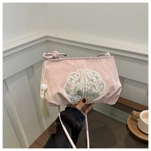 Detail of pink silk shoulder bag featuring white flower embroidery and green tassel