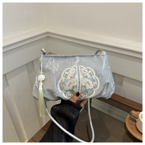 Detail of silver satin bag with floral embroidery and white jade flower tassel charm
