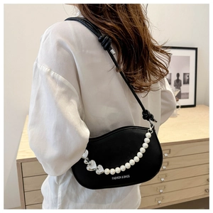 Detail of black matte leather shoulder bag with pearl pendant and heart charm