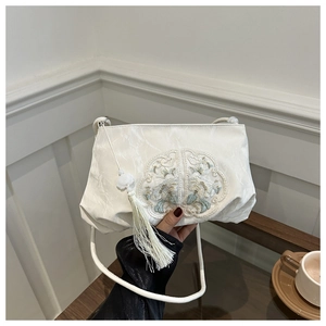 Detail of white satin shoulder bag with floral embroidery and elegant long tassel