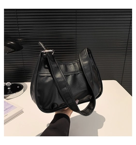Detailed close-up of a black pleated hobo bag with wide strap and silver metal buckle