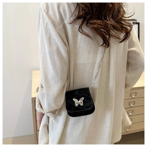 Close-up of mini black crossbody bag with silver chain and 3D butterfly metal buckle