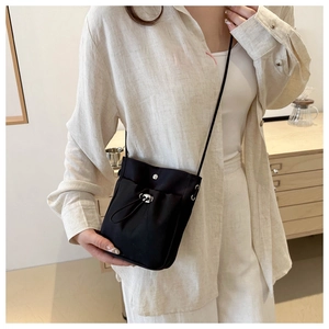 Detail van zwarte minimalistische crossbody tas met trekkoord en zilveren drukknopsluiting