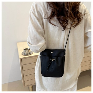 Detailopname van zwarte nylon mini crossbody telefoontas met trekkoord en drukknoop