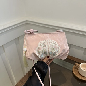 Pink Chinese style crossbody bag with floral embroidery and tassel on white backdrop