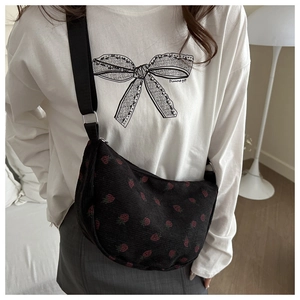 Detail of strawberry embroidery on black corduroy crossbody bag with adjustable strap