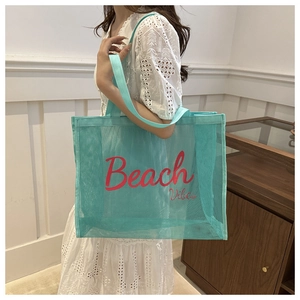 Detail of mint green mesh beach bag featuring red Beach Vibes text and large capacity