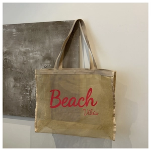 Detail shot of beige mesh tote bag with red Beach Vibes text and durable woven straps