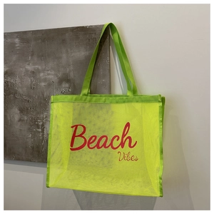 Detail of neon green mesh beach bag with red Beach Vibes text and breathable texture