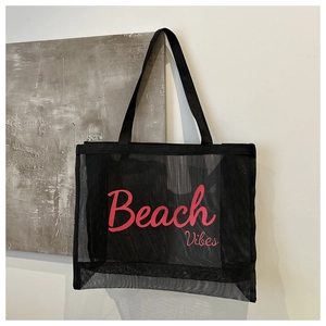 Close-up of black mesh tote bag featuring pink Beach Vibes text on a minimalist background