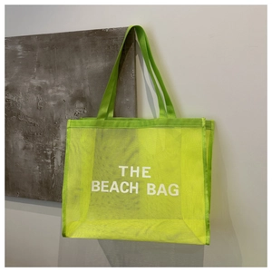 Close-up of fluorescent green mesh beach bag with white THE BEACH BAG lettering