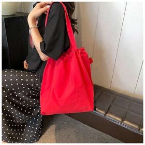 Detail of red canvas tote bag with drawstring closure and matching shoulder strap