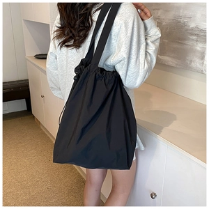 Detail of a large black nylon drawstring tote bag worn over the shoulder for commute
