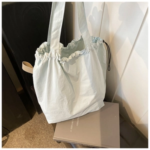 Detail of light green canvas tote bag with drawstring closure and black cord accents