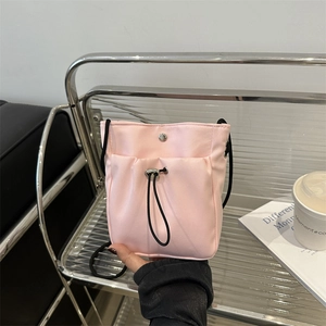 Roze nylon crossbodytas met trekkoord gepresenteerd op een modern metalen rek