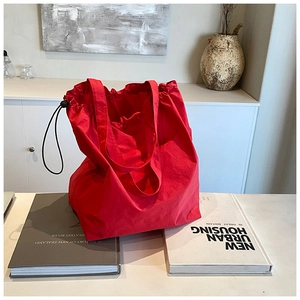 Close-up of red nylon tote bag featuring black drawstring closure and wrinkled texture