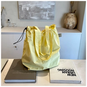 Detail of yellow drawstring tote bag with textured fabric and adjustable strap