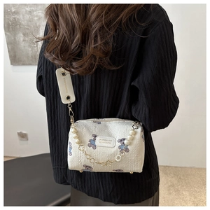 Detail of white mini crossbody bag with cute bear print and pearl strap decoration