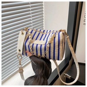 Detail of blue and white striped barrel bag with gold floral chain and leather tag