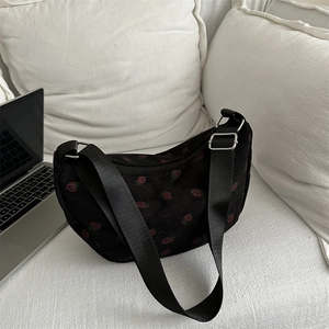 Corduroy strawberry print shoulder bag in black, resting by a laptop on a white pillow