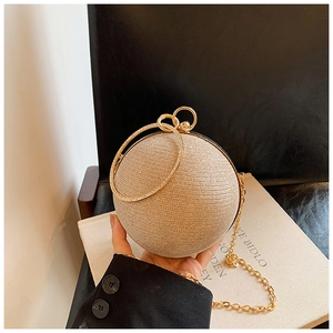 Detailed close-up of champagne gold spherical evening bag with metal ring and chain