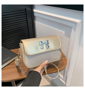 Close-up of champagne gold shoulder bag with metallic bow and glitter finish detail