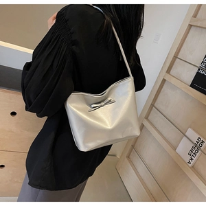 Silver metallic underarm bag with bow detail worn over shoulder with black top