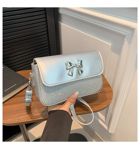 Detail of silver crossbody bag featuring a crystal finish and a metal bow clasp