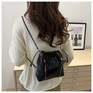 Détail d'un sac seau noir de style ballet avec chaînes argentées et détails de nœuds