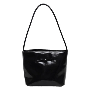 Minimalist black patent leather bucket bag with a bow detail for modern urban women