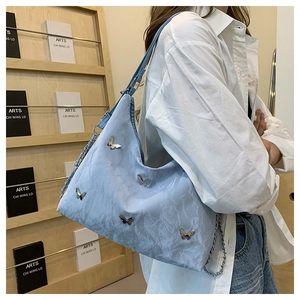 Detail of light blue pleated underarm bag featuring silver butterfly metal ornaments