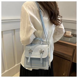 Detailed back view of a light blue crossbody bag with star buckles and contrast flap