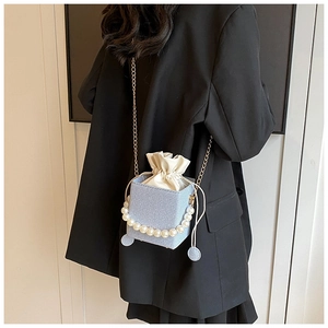 Détail du sac seau en denim bleu clair avec perles et bandoulière chaîne dorée