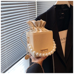 Détail de l'anse en perles et sac seau beige tissé avec bandoulière chaîne et cordon