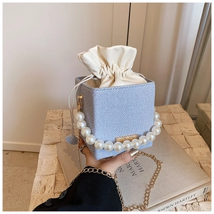 Détail du sac seau en tissu bleu et blanc avec poignée en perles et chaîne dorée