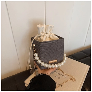 Détail du sac bandoulière gris avec poignée en perles et chaîne dorée sur livre