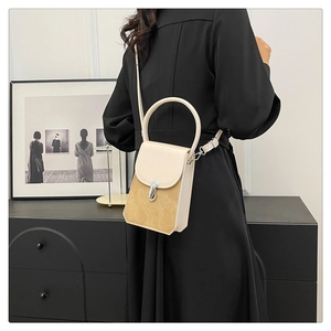 Detail view of two-tone crossbody bag with silver J-shaped buckle and top handle