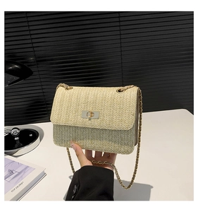 Détail d'un sac bandoulière en paille tressée avec fermoir doré et bandoulière chaîne