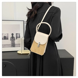 Detail of minimalist cream leather crossbody bag with distinctive semi-circular handle and silver lock