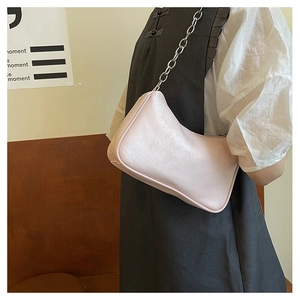 Detail of light pink shoulder bag with a chunky silver chain strap on a model