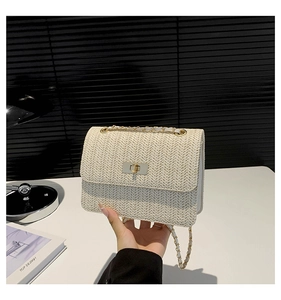 Détail du sac bandoulière tissé crème avec fermoir doré et bandoulière en chaîne
