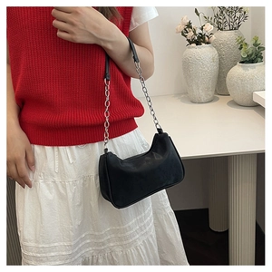 Chic black faux leather underarm bag with silver chain strap worn by a model
