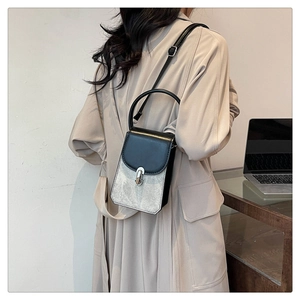 Model wearing a small two-tone black and silver leather crossbody bag with metal lock