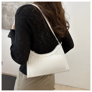 Detailed view of the white crescent shoulder bag showing its minimalist half-moon shape