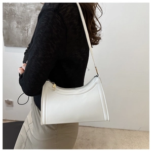 Side view of white minimalist baguette bag with gold hardware worn on the shoulder